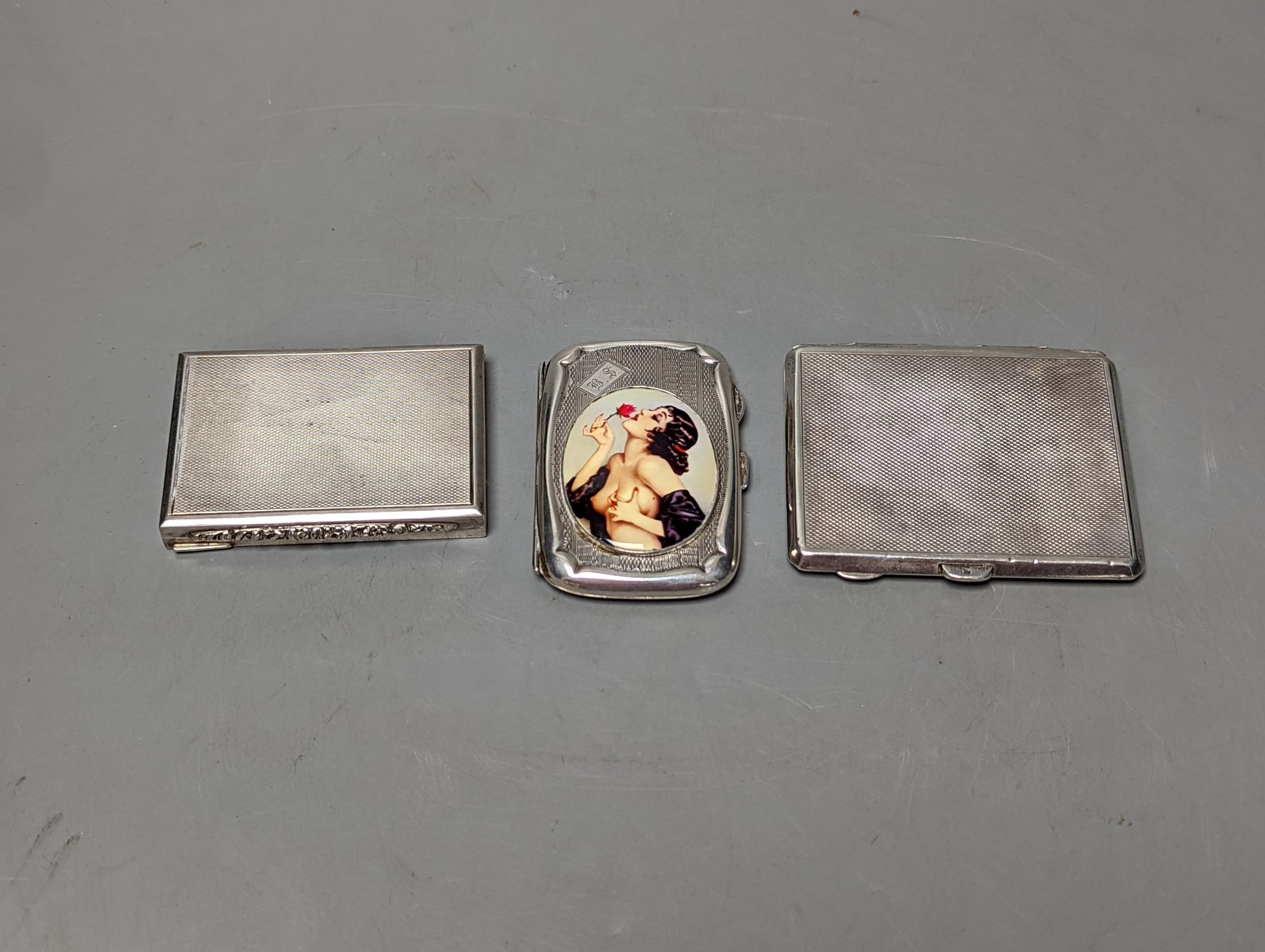 A silver cigarette case, an Austro Hungarian white metal box and a silver cigarette case with panel decorated with a topless lady, 77mm, gross weight 172 grams.